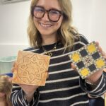 Mujer sonriente mostrando sus creaciones artesanales en el taller de marquetería nazarí de Arabesco Granada.