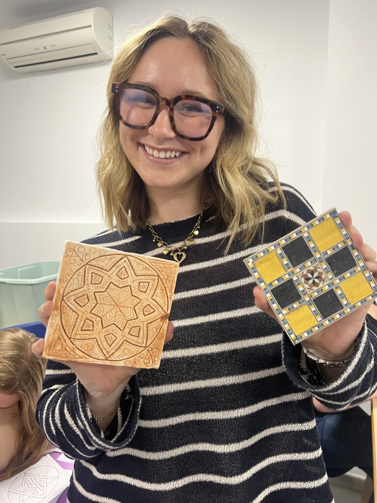 Mujer sonriente mostrando sus creaciones artesanales en el taller de marquetería nazarí de Arabesco Granada.
